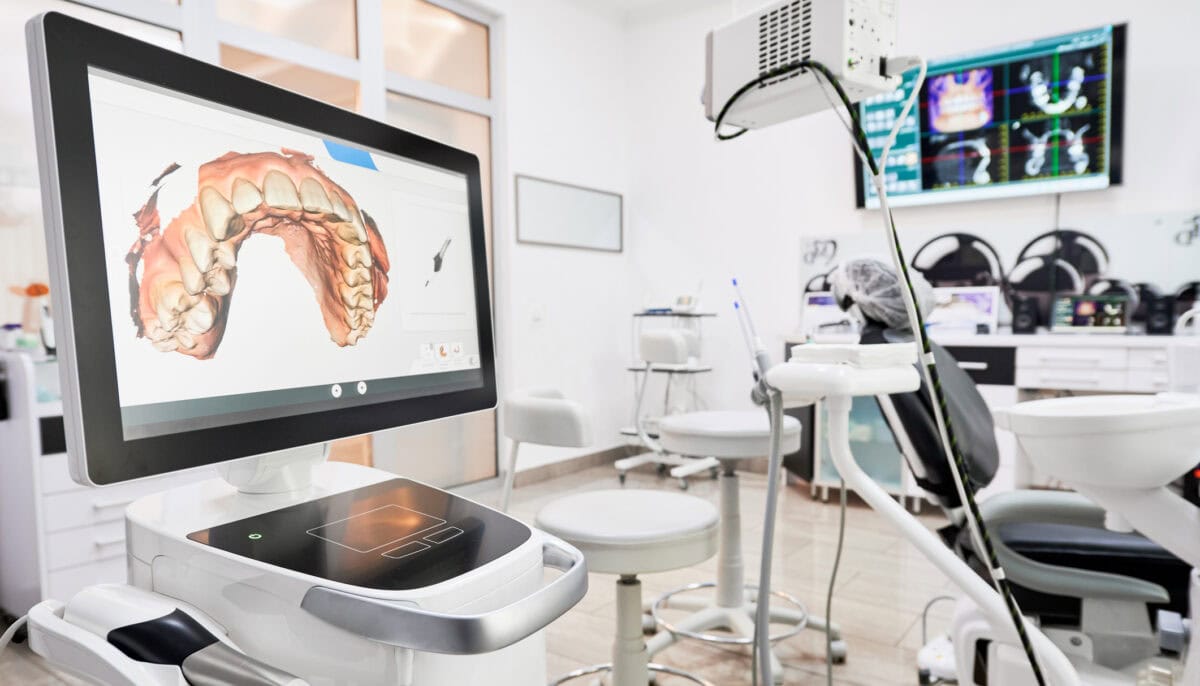 Interior of dental office with modern equipment and dental intraoral scanner with teeth on display, medical system for intraoral scanning. Concept of digital dentistry and dental scanning technology.