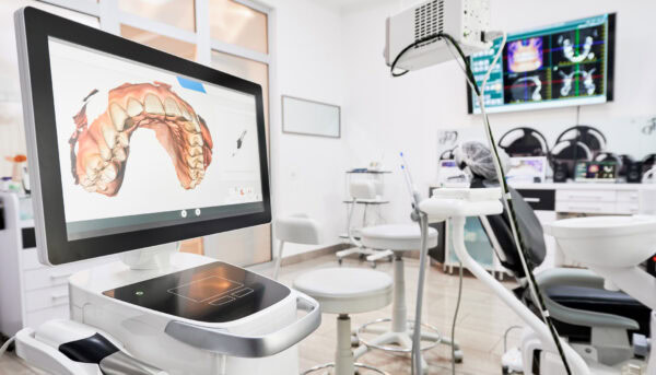 Interior of dental office with modern equipment and dental intraoral scanner with teeth on display, medical system for intraoral scanning. Concept of digital dentistry and dental scanning technology.