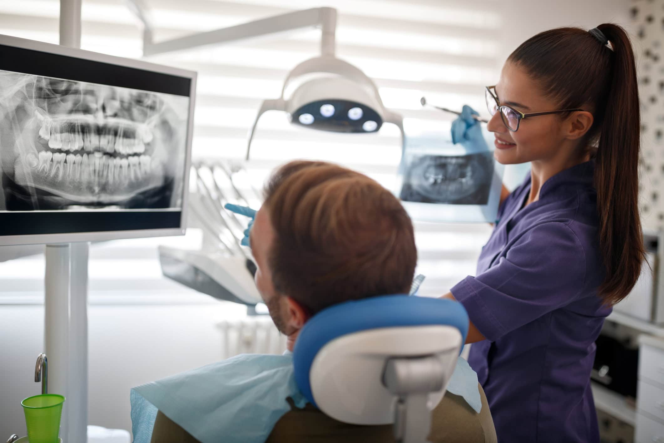 Female dentist explaining x-ray to her patient in dental clinic